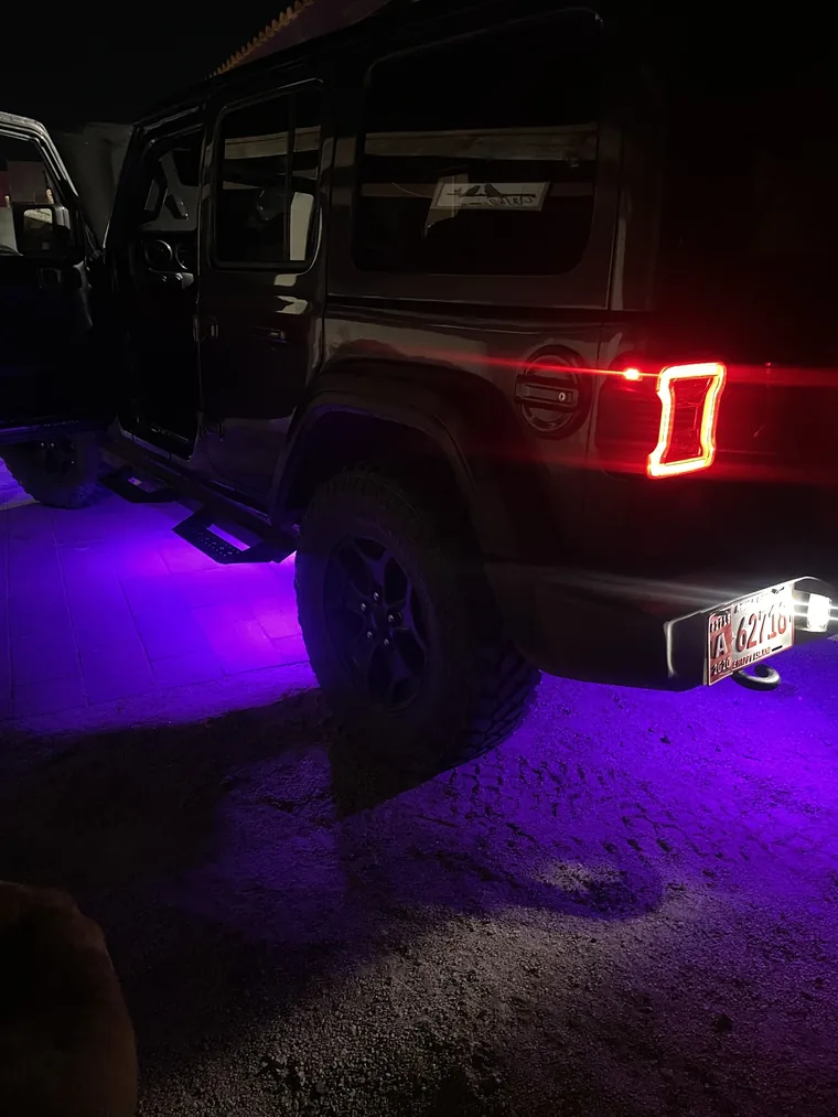 Purple underglow pooling on the ground under a Jeep at night
